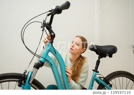 A woman examines a bicycle 139597110
