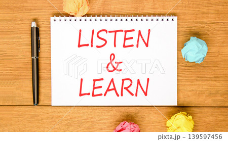 Listen and learn words symbol. Concept words Listen and learn on beautiful white note. Beautiful wooden background. Black pen. Colored paper. Business listen and learn support concept. Copy space. 139597456