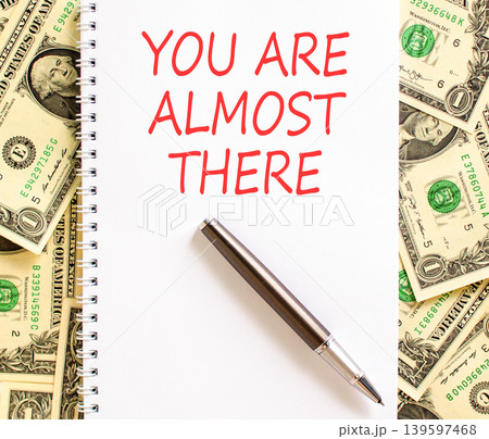 You are almost there words symbol. Concept words You are almost there on beautiful white note. Beautiful dollar bills background. Business You are almost there motivational support concept. Copy space 139597468