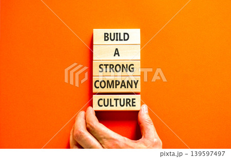 Strong company culture symbol. Concept words Build a strong company culture on beautiful wooden blocks. Beautiful orange paper background. Business strong company culture concept. Copy space. Strong company culture symbol. Concept words Build a strong company culture on beautiful wooden blocks. Beautiful orange paper background. Business strong company culture concept. Copy space. 139597497