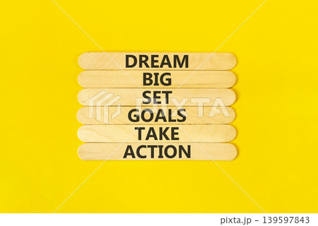 Dream big take action words symbol. Concept words Dream big Set goals Take action on beautiful wooden sticks. Beautiful yellow background. Business Dream big Set goals Take action concept. Copy space. 139597843