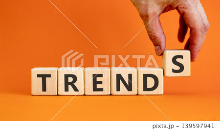 Trends trend word symbol. Concept word Trends on beautiful wooden blocks. Beautiful orange background. Businessman's hand. Business trends trend word concept. Copy space. Trends trend word symbol. Concept word Trends on beautiful wooden blocks. Beautiful orange background. Businessman's hand. Business trends trend word concept. Copy space. 139597941