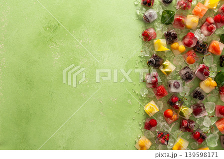Green background with ice cubes with frozen berries and fruits and mint Green background with ice cubes with frozen berries and fruits and mint 139598171