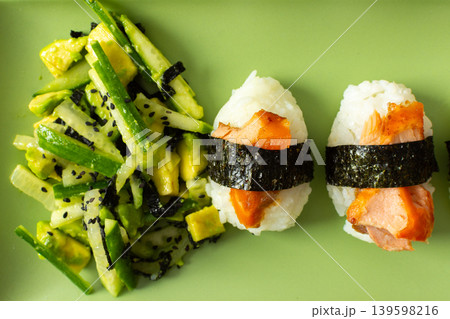 A plate shows a salad made with nori, fresh cucumbers, and avocado next to nigiri sushi topped with red fish. This dish is suitable for breakfast or lunch A plate shows a salad made with nori, fresh cucumbers, and avocado next to nigiri sushi topped with red fish. This dish is suitable for breakfast or lunch 139598216