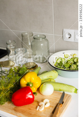 Cucumbers, peppers, and zucchini are being prepared and placed in jars for canning. Fresh ingredients are cut and organized on a clean kitchen counter for preserving Cucumbers, peppers, and zucchini are being prepared and placed in jars for canning. Fresh ingredients are cut and organized on a clean kitchen counter for preserving 139598222