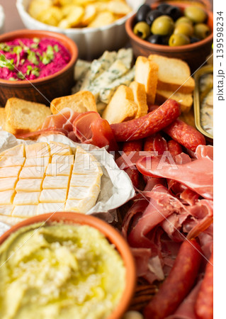 Taste a variety of flavors with this charcuterie board filled with cheese, sausages, hummus, nuts, and fresh sandwiches, perfect for any gathering Taste a variety of flavors with this charcuterie board filled with cheese, sausages, hummus, nuts, and fresh sandwiches, perfect for any gathering 139598234