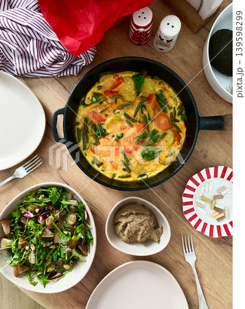Baked vegetables with eggs sit on a plate next to a salad made from arugula and Brussels sprouts. A bowl of liver pate completes the meal with healthy choices Baked vegetables with eggs sit on a plate next to a salad made from arugula and Brussels sprouts. A bowl of liver pate completes the meal with healthy choices 139598299