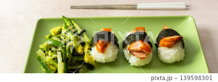 A plate shows a salad made with nori, fresh cucumbers, and avocado next to nigiri sushi topped with red fish. This dish is suitable for breakfast or lunch, banner A plate shows a salad made with nori, fresh cucumbers, and avocado next to nigiri sushi topped with red fish. This dish is suitable for breakfast or lunch, banner 139598301