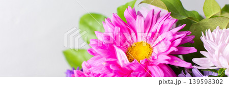 A group of flowers in shades of pink, purple, and white are gathered in a vase. The vase rests on a table. The setting is bright and shows the flowers clearly, banner A group of flowers in shades of pink, purple, and white are gathered in a vase. The vase rests on a table. The setting is bright and shows the flowers clearly, banner 139598302