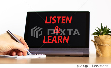 Listen and learn words symbol. Concept words Listen and learn on beautiful black tablet. Beautiful white background. Businessman hand. Business listen and learn support concept. Copy space. 139598366