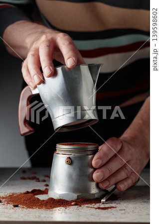 Man is prepared coffee in a classic Italian aluminium moka pot. Man is prepared coffee in a classic Italian aluminium moka pot. 139598602