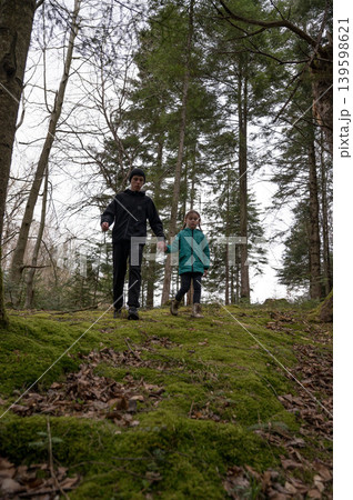 Exploring the lush green trails of a serene forest during a crisp autumn day with a child in joyful companionship Exploring the lush green trails of a serene forest during a crisp autumn day with a child in joyful companionship 139598621