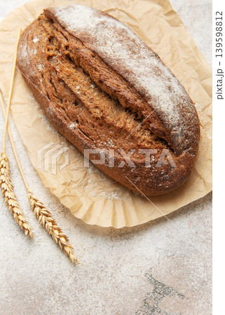 Rye bread loaf with wheat ears on parchment paper Rye bread loaf with wheat ears on parchment paper 139598812