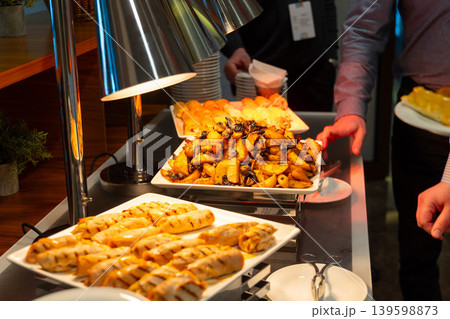 Person serving roasted potatoes from a buffet station Person serving roasted potatoes from a buffet station 139598873