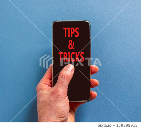 Tips and tricks words symbol. Concept words Tips and tricks on beautiful phone screen. Beautiful blue background. Businessman hand. Business tips and tricks motivational support concept. Copy space. Tips and tricks words symbol. Concept words Tips and tricks on beautiful phone screen. Beautiful blue background. Businessman hand. Business tips and tricks motivational support concept. Copy space. 139598915