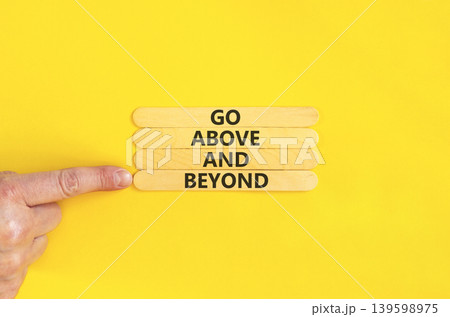Go above and beyond symbol. Concept words Go above and beyond on beautiful wooden sticks. Beautiful yellow background. Businessman hand. Business motivational Go above and beyond concept. Copy space. 139598975