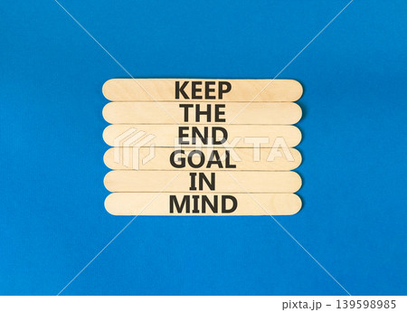 Keep the end goal in mind symbol. Concept words Keep the end goal in mind on beautiful wooden sticks. Beautiful blue paper background. Business keep the end goal in mind concept. Copy space. 139598985