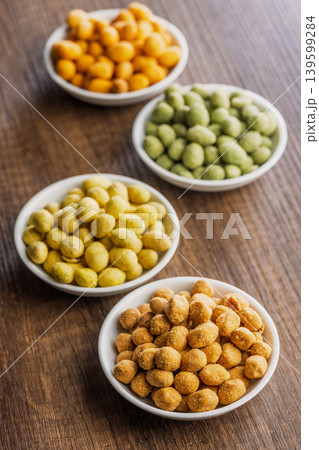 Assorted Coated Peanuts in White Bowls on Wooden Table - Crunchy Flavored Snack Mix 139599284