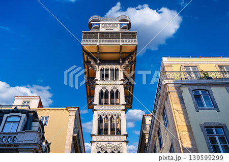 Upshot of Santa Justa Lift or Carmo lift elevator in historic center, Lisbon, Portugal connecting Baixa district with Largo do Carmo on sunny day. Iron tower, blue sky with clouds, iconic city Upshot of Santa Justa Lift or Carmo lift elevator in historic center, Lisbon, Portugal connecting Baixa district with Largo do Carmo on sunny day. Iron tower, blue sky with clouds, iconic city 139599299