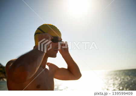 Sports, beach and man for swimming exercise, nature workout or outdoor practice in ocean, sea or water waves. Mockup sky space, goggles and swimmer for challenge, fitness performance or summer cardio 139599409
