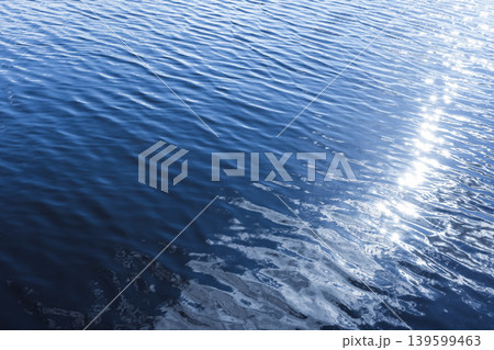 Serene closeup of deep blue water showing gentle ripples and bright sunlight reflections Serene closeup of deep blue water showing gentle ripples and bright sunlight reflections 139599463