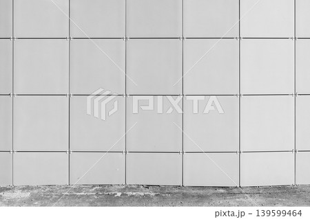 Minimal architectural facade showing a grid of square metal panels with visible joints 139599464