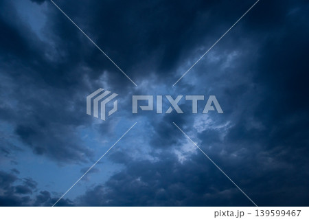 Dramatic dark storm clouds dominate a moody blue sky at dusk, natural background Dramatic dark storm clouds dominate a moody blue sky at dusk, natural background 139599467