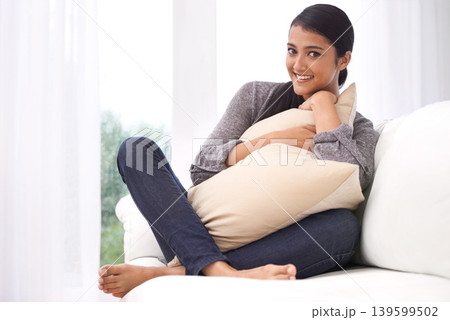 Woman, sofa and portrait in a home with pillow hug, smile and happy from calm morning. House, couch and calm in a living room and lounge with an Indian female person in a condo with peace and joy Woman, sofa and portrait in a home with pillow hug, smile and happy from calm morning. House, couch and calm in a living room and lounge with an Indian female person in a condo with peace and joy 139599502