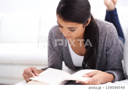 Young woman, reading book on sofa and learning for home education, literature or language with leisure. Student or person relax in living room or lounge with novel or story for knowledge or studying 139599549