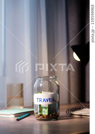 Savings jar for TRAVEL on table. Close up of money in transparent container representing financial planning and goal achievement Savings jar for TRAVEL on table. Close up of money in transparent container representing financial planning and goal achievement 139599968