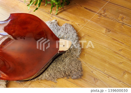 Broken contrabass neck joint area on wooden floor with wool fleece rug close up with copy space 139600030
