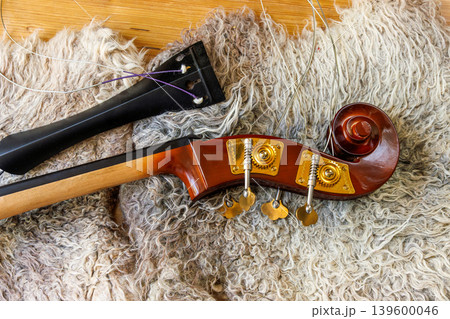 Detached contrabass neck joint with fingerboard, tailpiece  and scroll with pegbox on felted wool locks blanket. Top view 139600046