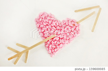 Symbol of Valentine's Day. Heart made of wax granules. Pink heartshaped wax granules for depilation on a white background. 139600085