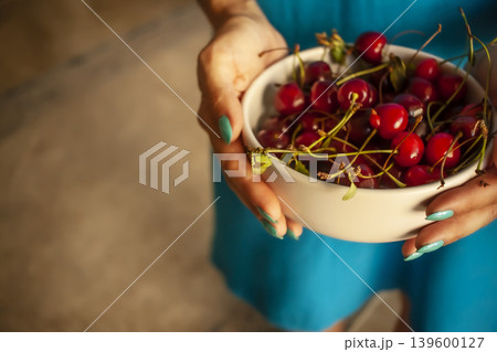 The girl holds a plate with cherries. The girl holds a plate with cherries. 139600127