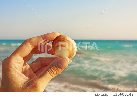 Hand with shell on sea background 139600148