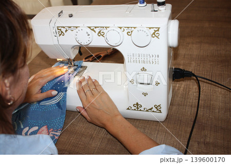 A girl sews on a sewing machine A girl sews on a sewing machine 139600170