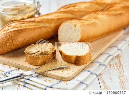 French bread baguette with liver pate curls on a kitchen table, selective focus. 139600327