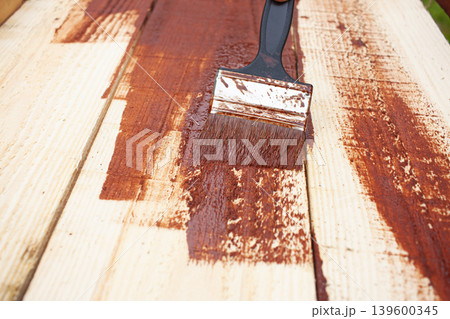 Close-up of a Brush Painting Wood in Brown Color. Painting of wooden boards, impregnation of wood 139600345