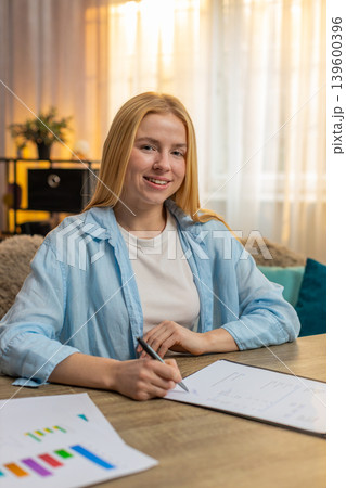 Young woman signing contract at home, satisfaction, reading carefully, final approval, deal done 139600396