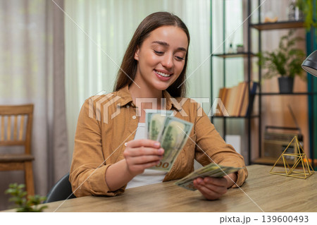 Young woman counting money dollars cash satisfied with salary earnings celebrating financial success Young woman counting money dollars cash satisfied with salary earnings celebrating financial success 139600493