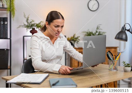 Young businesswoman faces laptop freeze presses keyboard no response shows despair and hold head Young businesswoman faces laptop freeze presses keyboard no response shows despair and hold head 139600515