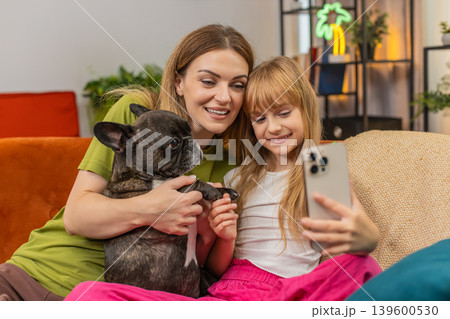 Mother daughter dog selfie joke with smartphone filter mask laugh together make faces playful family 139600530