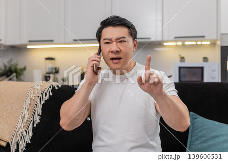 Asian man argues on smartphone frowns shows no no finger gesture speaks firmly and rejects request 139600531