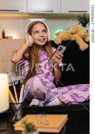 Teenager girl enjoys music with wireless headphones from smartphone smiles moves dances happy rhythm Teenager girl enjoys music with wireless headphones from smartphone smiles moves dances happy rhythm 139600681