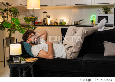 Arabian man lies back with feet up smiles enjoys rest carefree evening relaxed indoors very peaceful 139600683