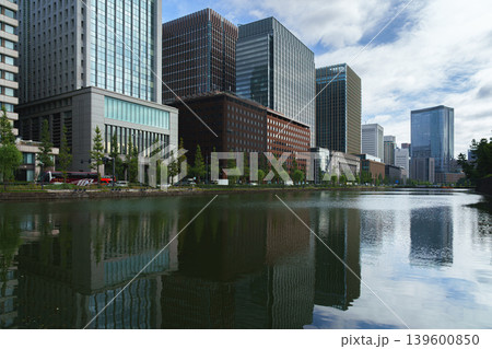 Tokyo, Japan - Oct 1 2024, panoramic view of the skyscraper facades of the Chiyoda district, with reflections of buildings visible in pond in the foreground, at daytime, Tokyo, Japan Tokyo, Japan - Oct 1 2024, panoramic view of the skyscraper facades of the Chiyoda district, with reflections of buildings visible in pond in the foreground, at daytime, Tokyo, Japan 139600850