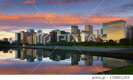 Tokyo, Japan - Oct 1 2024, panoramic view of skyscrapers of Chiyoda district, with a moat in foreground with mirror-like water reflecting buildings and sky, and colorful clouds in sky at sunset, Tokyo Tokyo, Japan - Oct 1 2024, panoramic view of skyscrapers of Chiyoda district, with a moat in foreground with mirror-like water reflecting buildings and sky, and colorful clouds in sky at sunset, Tokyo 139601205