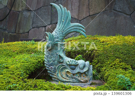 Tokyo, Japan - Oct 1 2024, close-up view of a bronze sculpture of the mythical creature shachihoko, placed among bushes near a stone wall on the grounds of the Tokyo Imperial Palace, Tokyo, Japan Tokyo, Japan - Oct 1 2024, close-up view of a bronze sculpture of the mythical creature shachihoko, placed among bushes near a stone wall on the grounds of the Tokyo Imperial Palace, Tokyo, Japan 139601306