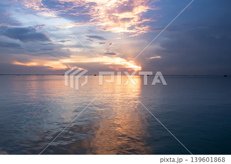Soft blue and peach sunset tones spread across a calm lake, with gentle ripples reflecting the glowing sky and layered clouds stretching over a distant horizon. Soft blue and peach sunset tones spread across a calm lake, with gentle ripples reflecting the glowing sky and layered clouds stretching over a distant horizon. 139601868