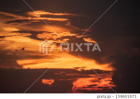 Close-up of blazing sunset clouds with rich orange and red tones, contrasted by deep shadowed formations, creating a powerful and textured sky full of intensity and depth. Close-up of blazing sunset clouds with rich orange and red tones, contrasted by deep shadowed formations, creating a powerful and textured sky full of intensity and depth. 139601873
